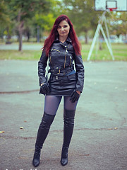 In an autumn park, the redheaded girl named Jeny removes her skirt to pose seductively in her seamless blue pantyhose, wearing only a leather jacket and high boots